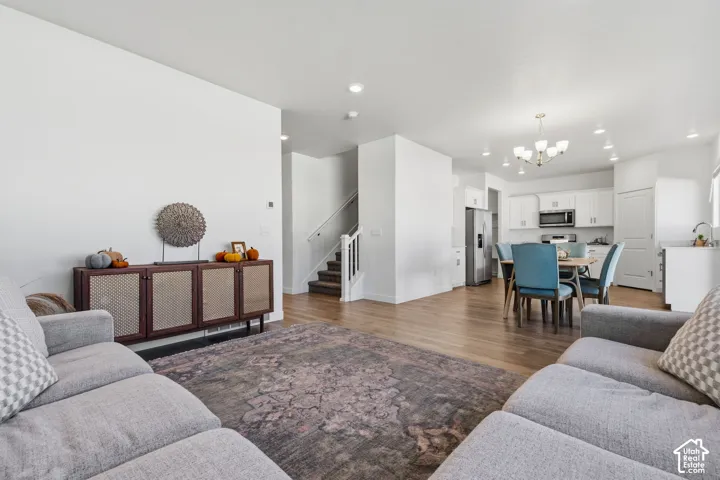 Open-concept living space featuring wood-finish laminate flooring, recessed lighting, white cabinetry, and stainless steel appliances