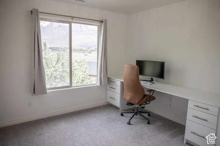 Built-in desk featuring multiple drawers, large window with outdoor scenery, and light-colored wall paint