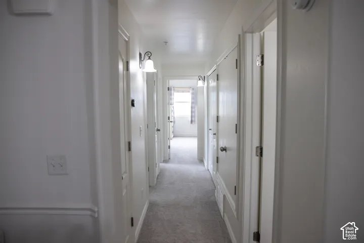 Hallway featuring a neutral color palette, recessed lighting, wall sconces, and light gray carpeting