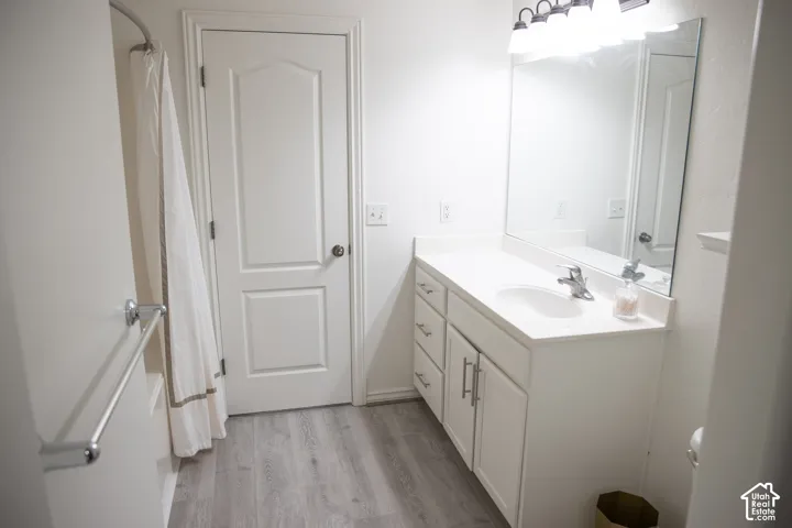 White vanity with integrated sink, chrome faucet, and expansive mirror