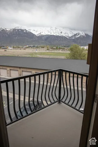 Balcony with a concrete floor, black metal railing, and distant snow-capped mountains