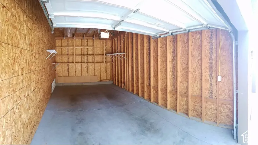 Garage space with concrete flooring, exposed wood wall framing, and a white overhead door