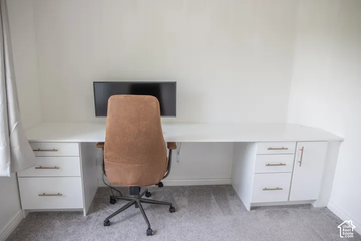 Integrated built-in desk with white cabinetry, three drawers, and a storage cabinet, all featuring gold-tone hardware