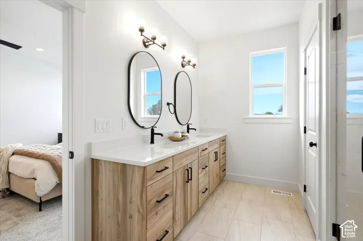 Dual vanity with wood-finish cabinetry, white countertops, and matte black fixtures