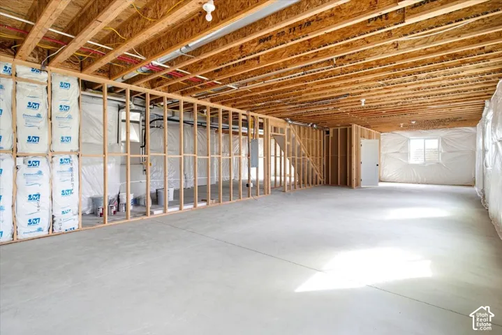Unfinished basement with exposed ceiling joists, concrete flooring, framed interior walls, and wall insulation