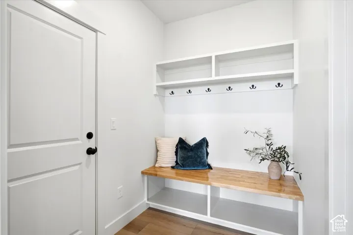 Built-in bench with wood-finish top, white shelving, and coat hooks