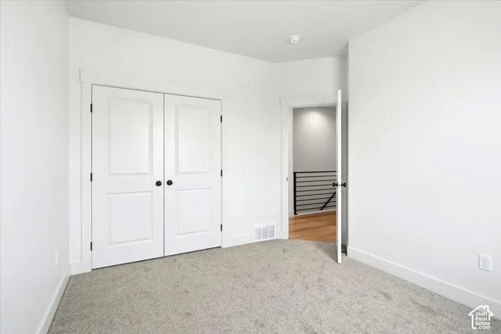 Carpeted room with white walls, white trim, and two-panel closet doors