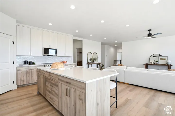 Open-concept living area with wood-finish flooring, recessed lighting, and a ceiling fan