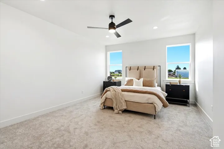 Recessed lighting, ceiling fan with integrated lighting, two windows, and carpeted flooring