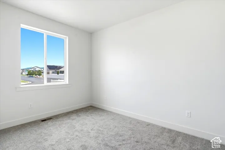 White walls, a large window, and gray carpet flooring