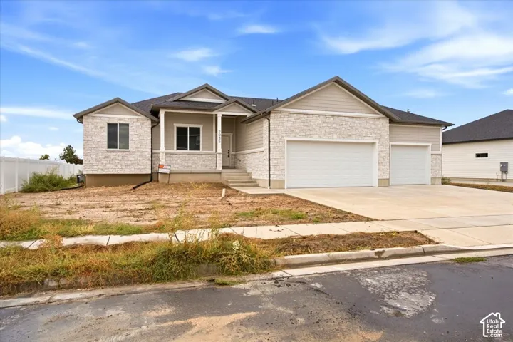 Exterior featuring light-toned stone and siding accents, a covered front porch, and a two-car attached garage