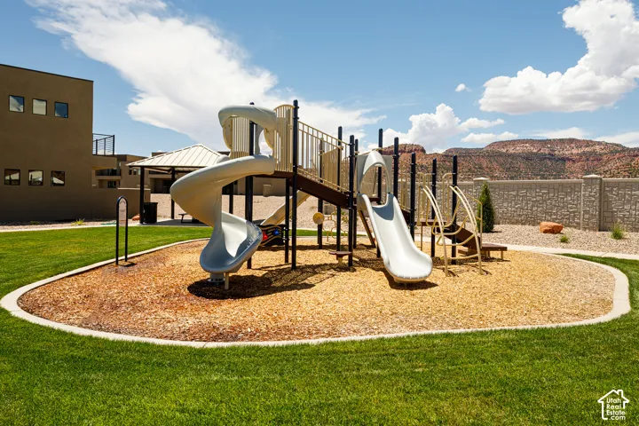 Outdoor playground with multiple slides, wood chip surfacing, and a surrounding lawn area