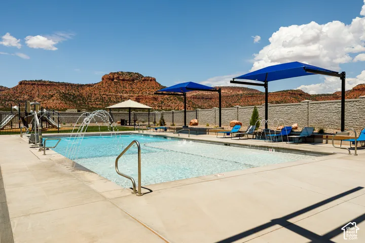 Swimming pool featuring a water fountain, multiple shade structures, and surrounding concrete decking