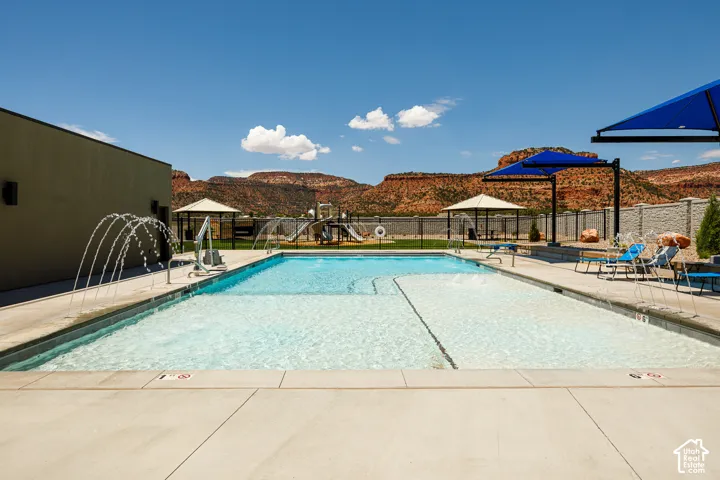 Expansive outdoor swimming pool with water features, surrounding concrete decking, and red rock mountain backdrop