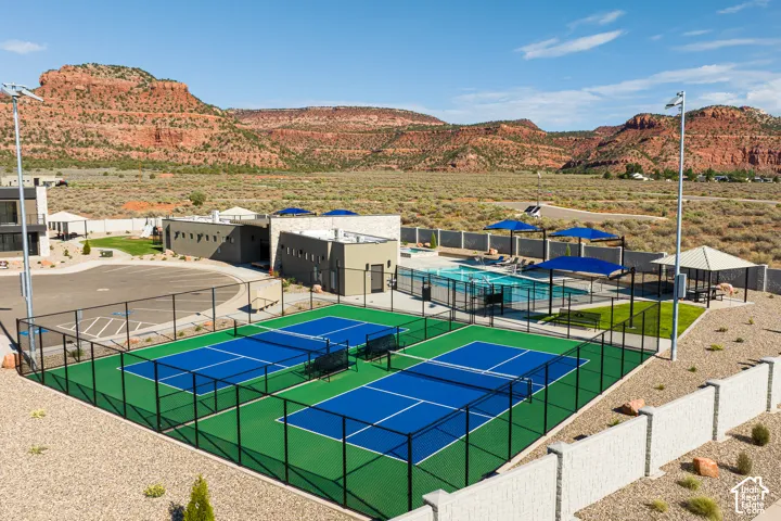 Dual outdoor pickleball courts, fenced swimming pool, shaded pool deck, outdoor gazebo, and modern community buildings