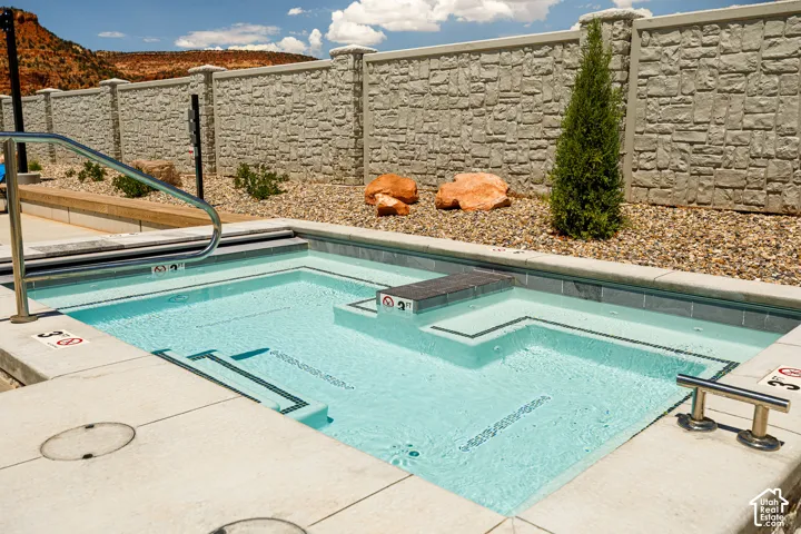 Integrated pool and spa featuring a patterned tile interior and concrete coping
