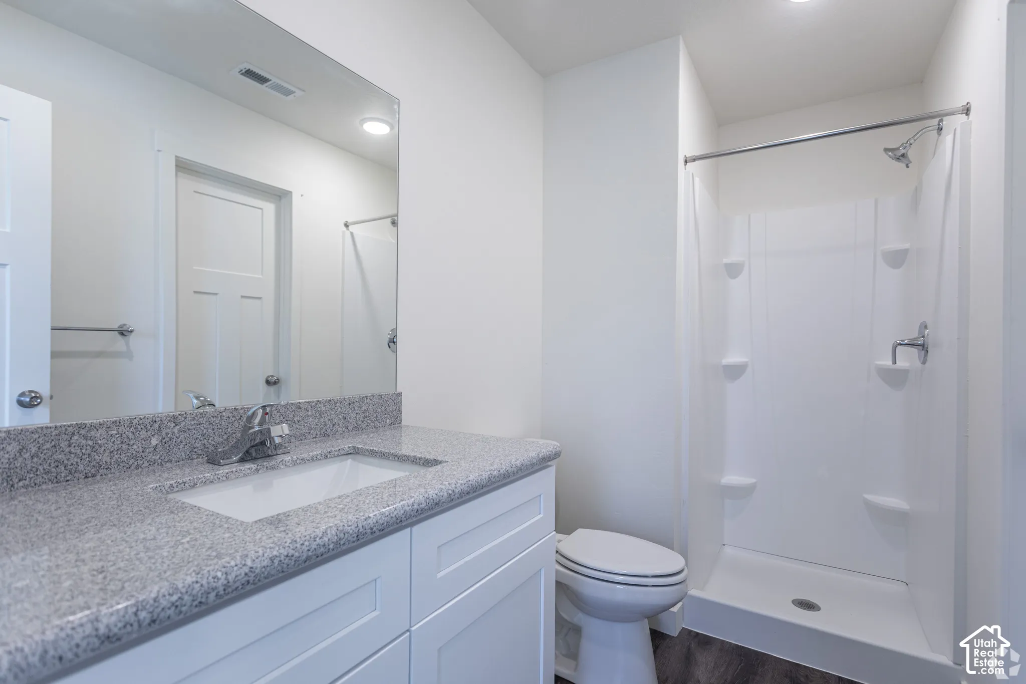 White vanity with a light-toned stone countertop and undermount sink