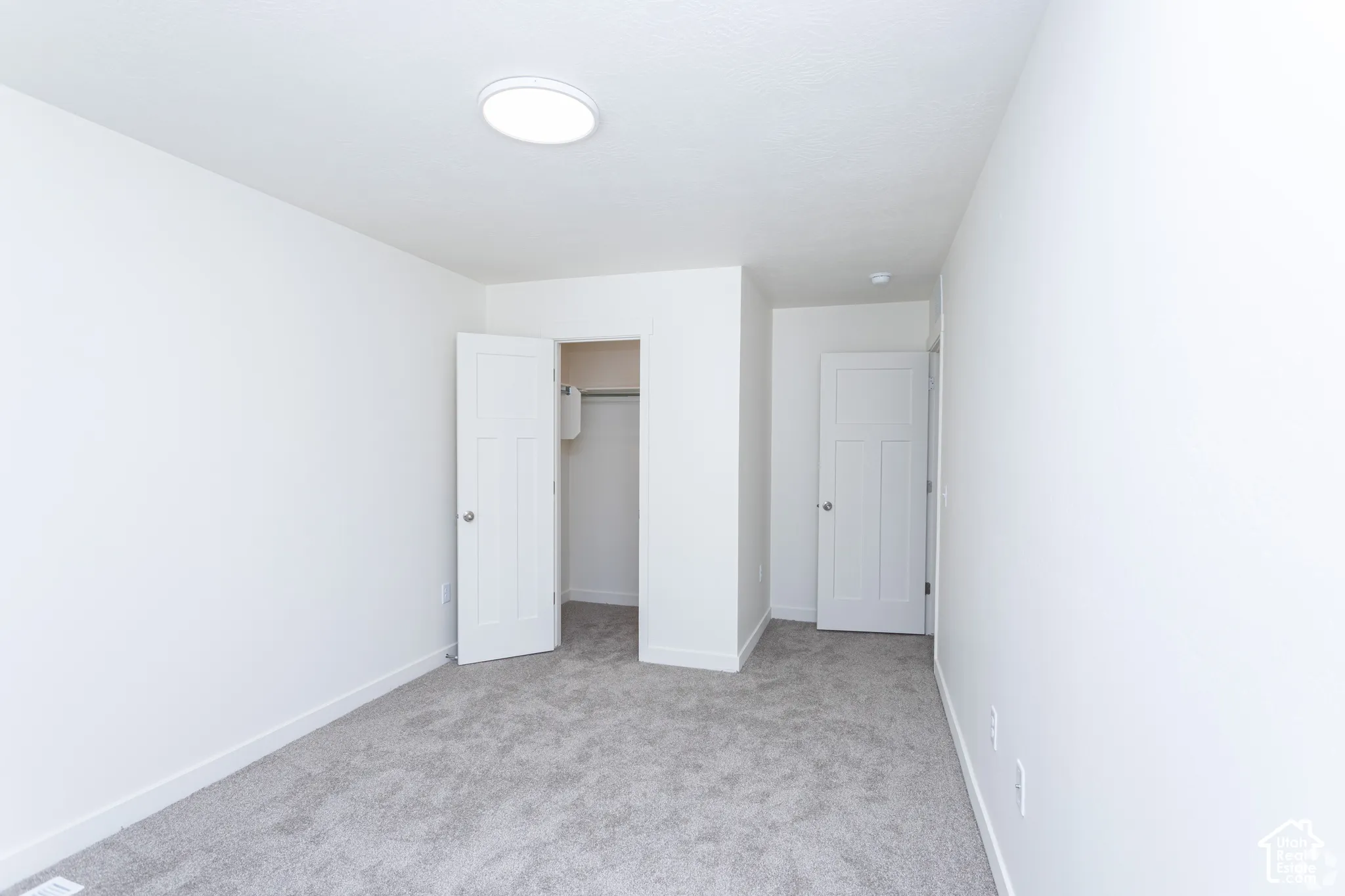 Neutral wall color, gray carpeting, interior doors, and a flush-mount ceiling light fixture
