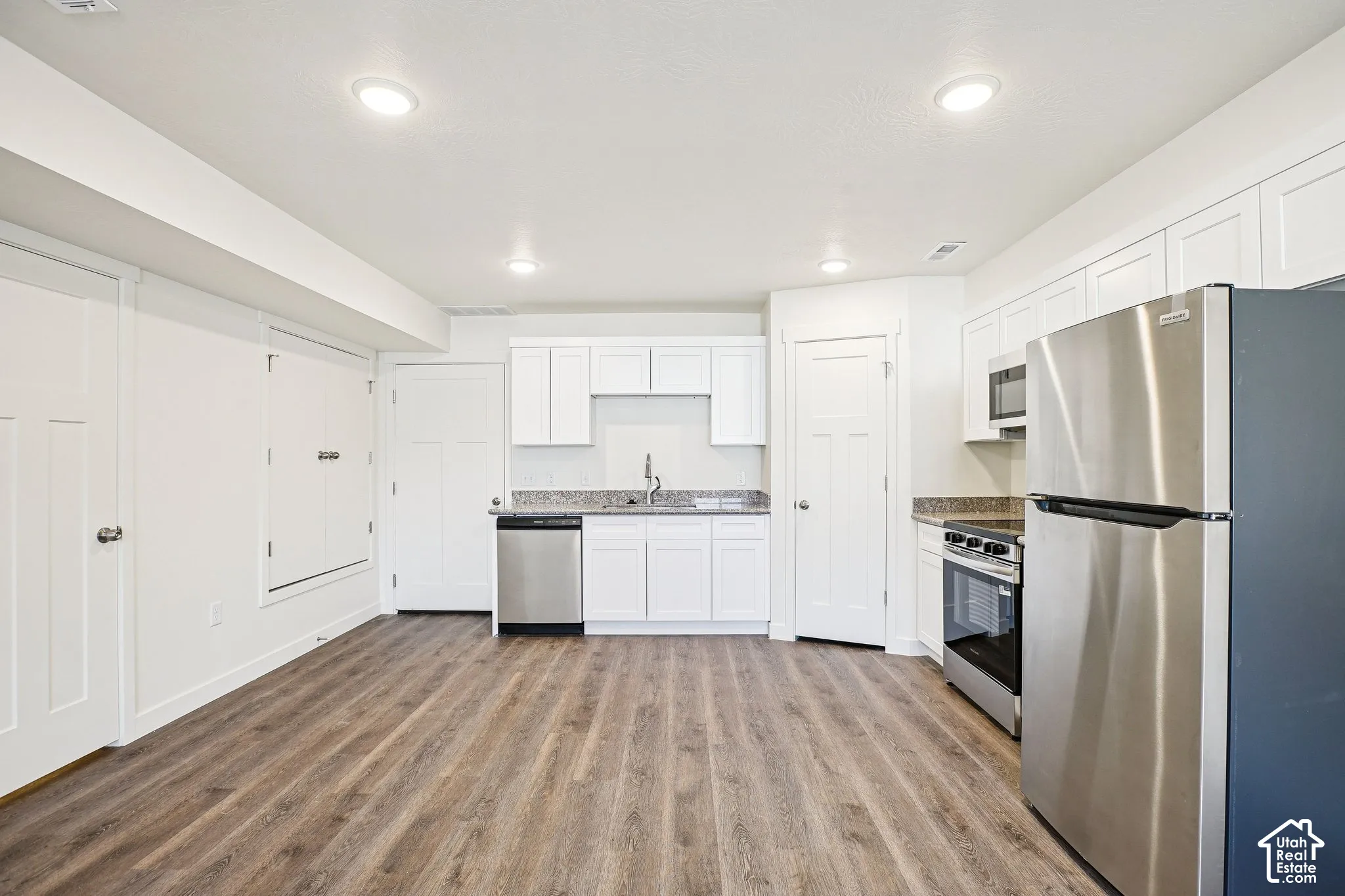 Kitchen featuring wood-finish flooring, white cabinetry, stainless steel appliances, and recessed lighting
