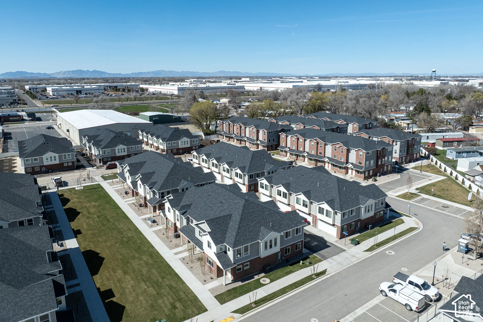 Modern townhome community featuring multi-story units with attached garages, individual balconies, and a central green space