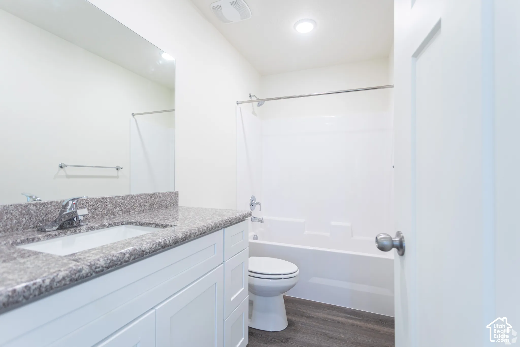 Vanity with a polished chrome faucet, under-mount sink, and speckled countertop