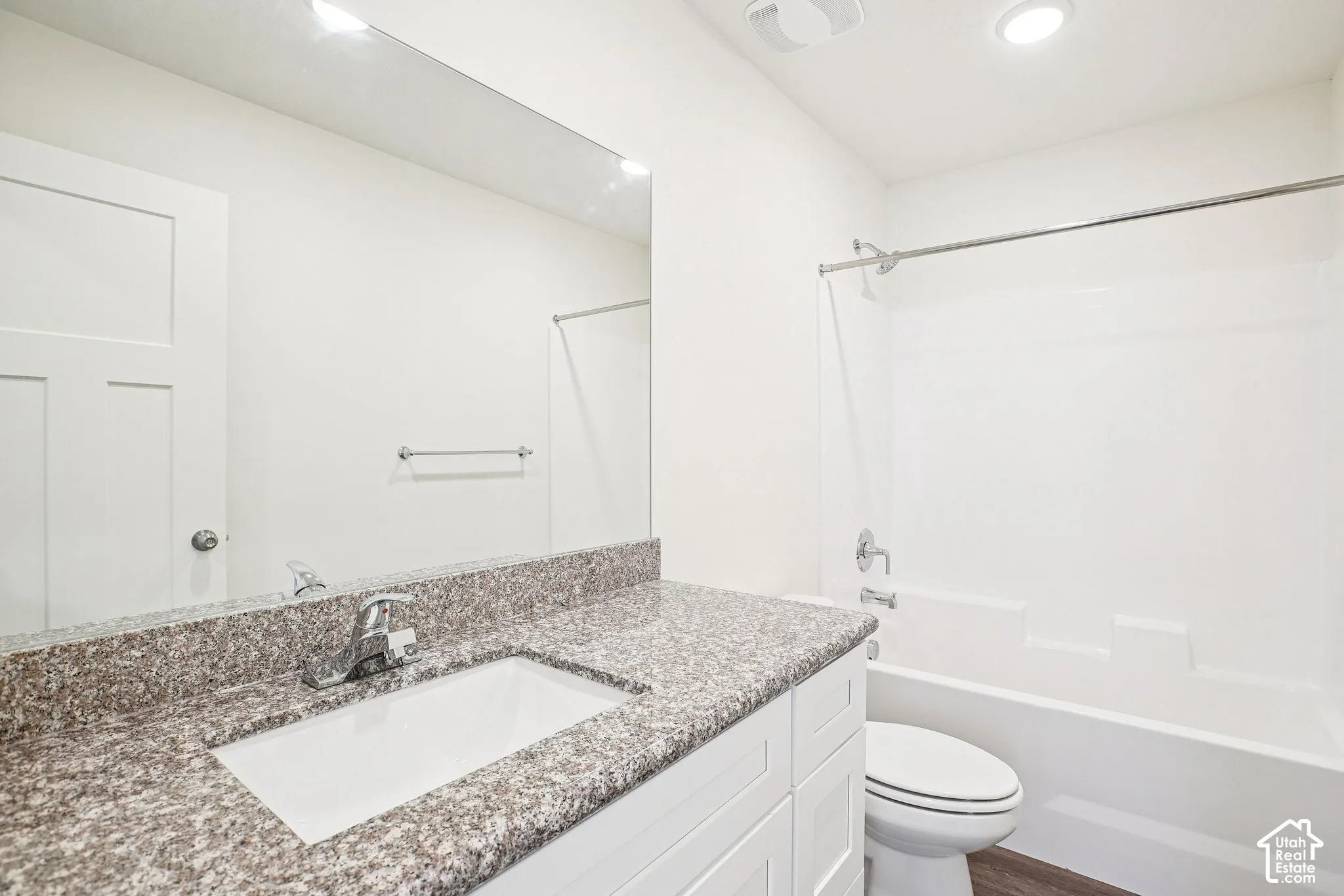 White vanity with a granite-style countertop, undermount sink, and chrome faucet