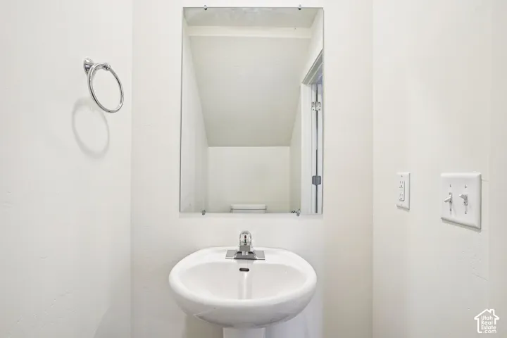 Pedestal sink with chrome-finish faucet, wall-mounted mirror, and chrome-finish towel ring