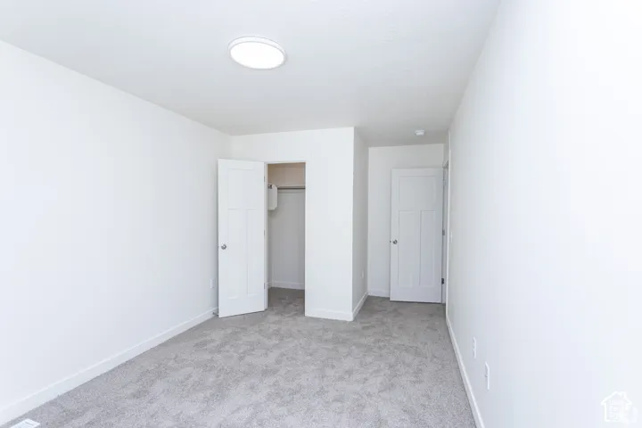 Neutral wall color, gray carpeting, interior doors, and a flush-mount ceiling light fixture