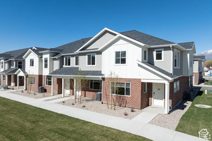 Townhome exterior featuring brick and stucco siding, white trim accents, and a dark shingle roof