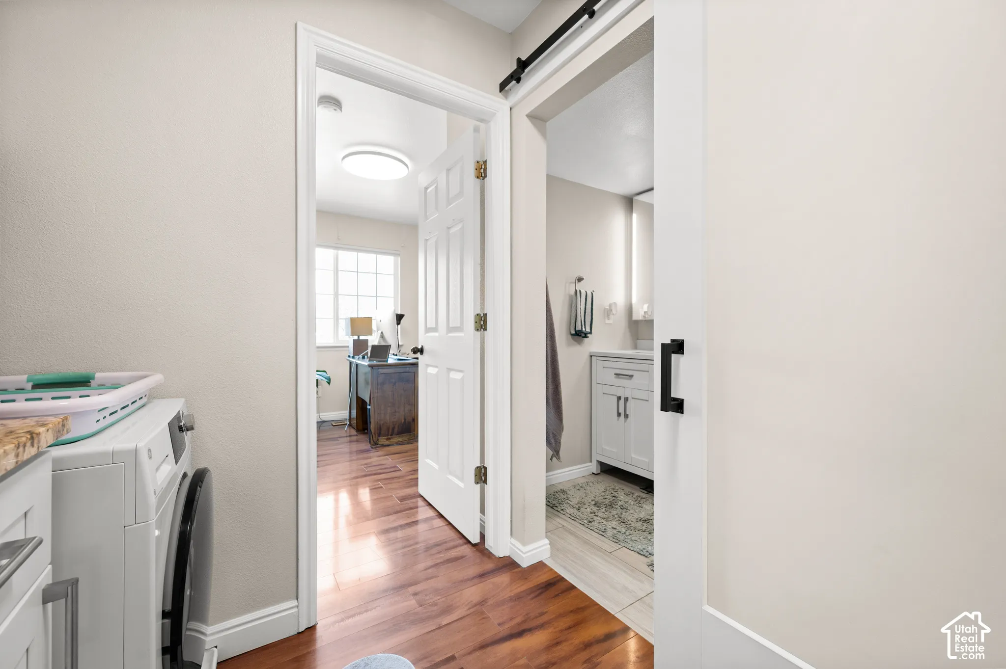 Wood-finish flooring, white paneled doors, and a sliding barn door with black hardware