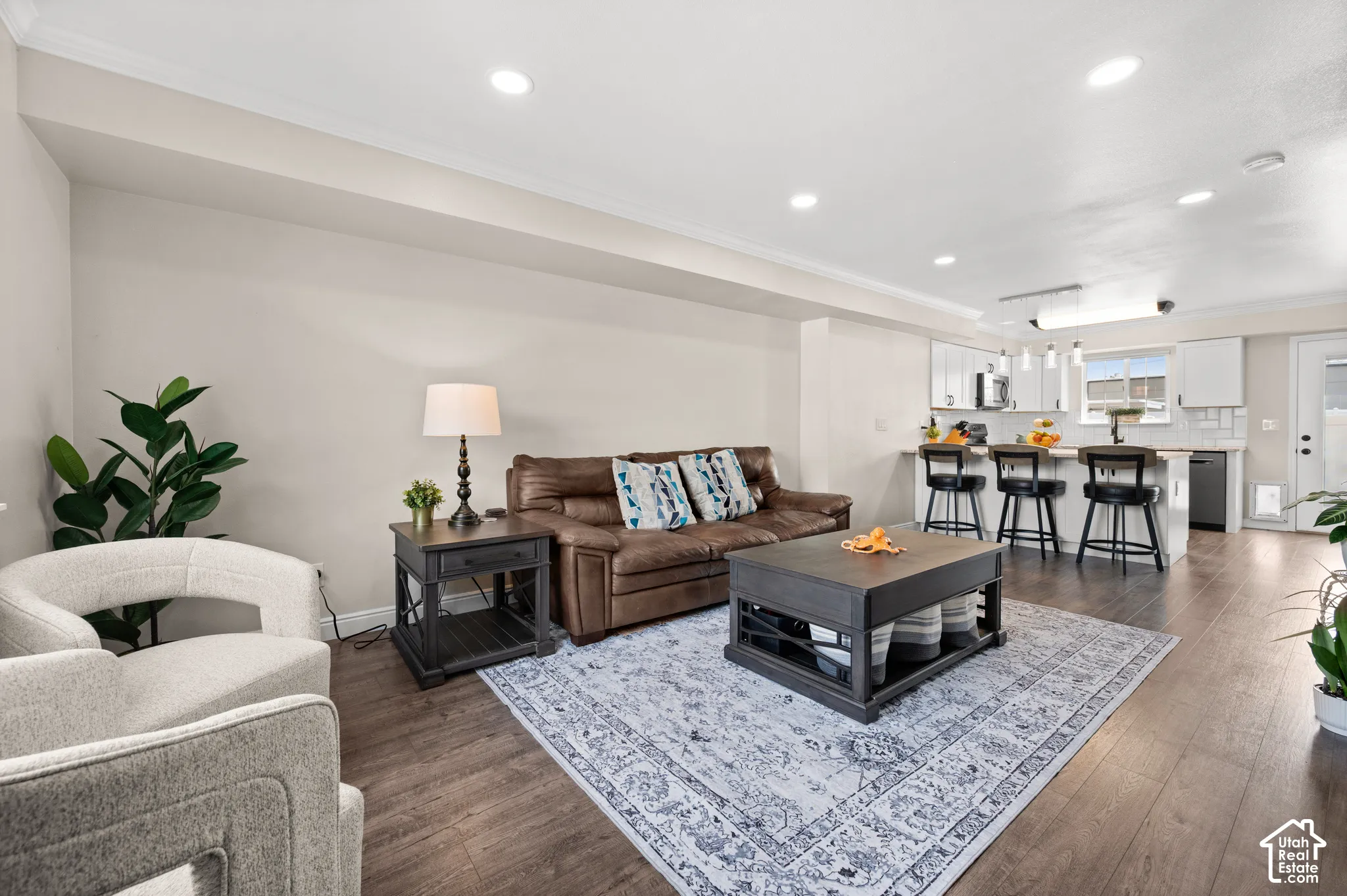 Recessed lighting, wood-finish flooring, white kitchen cabinetry, and a kitchen island with bar seating