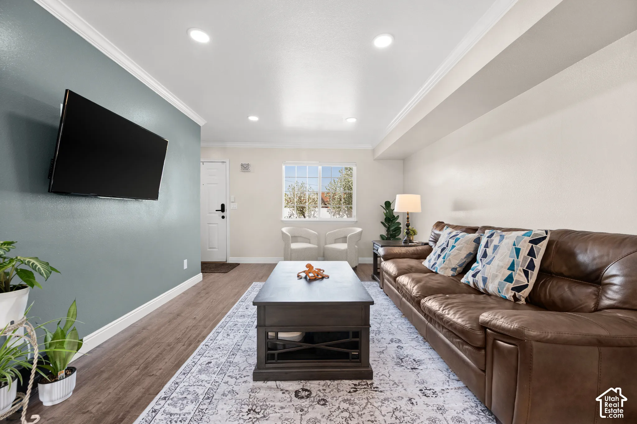 Recessed ceiling lighting, crown molding, wood-finish flooring, a front entry door, and a prominent window