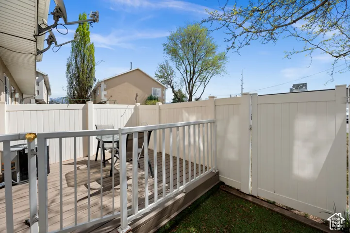 Private outdoor deck featuring wood-finish decking and white railing, enclosed by a privacy fence