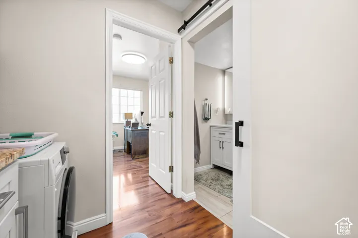 Wood-finish flooring, white paneled doors, and a sliding barn door with black hardware