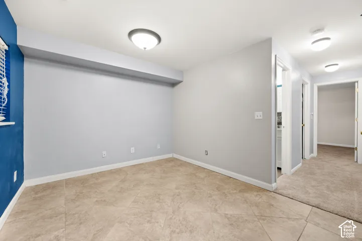 Recessed ceiling with flush mount lighting, tiled flooring, carpeting, and multiple doorways