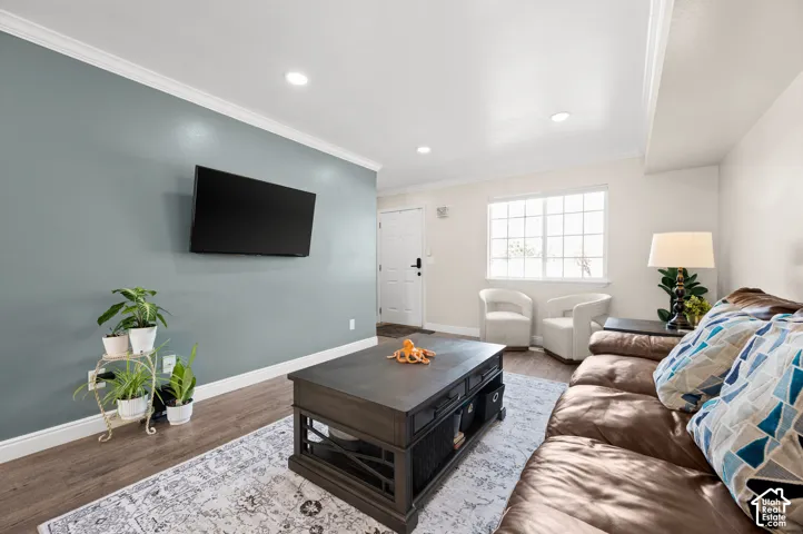 Recessed lighting, wood-finish flooring, crown molding, paneled door, and a multi-pane window