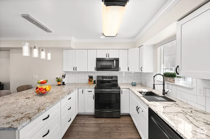 Kitchen featuring white shaker cabinetry, light-toned countertops, subway tile backsplash, and black appliances