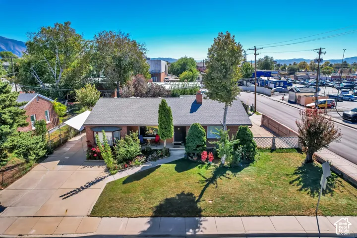 Brick exterior with a gabled roof, mature landscaping, paved driveway, and covered porch