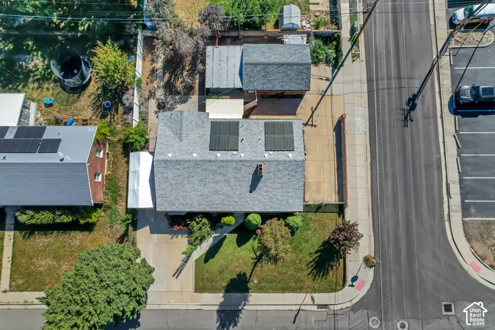 Gable roof with solar panels, attached carport, concrete driveway, front lawn, and mature landscaping