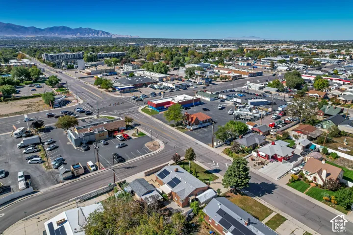 Expansive aerial perspective showcasing a residential area with mixed commercial properties, established roads, and distant mountain ranges