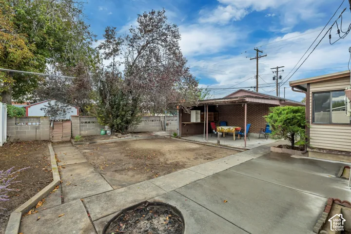 Paved concrete patio area with a covered outdoor space and brick accent wall