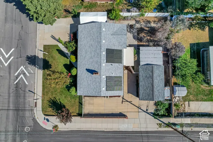 Pitched roof with solar panels, attached carport, paved driveway, and manicured front lawn