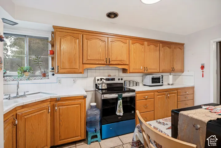 Wood-finish cabinetry with silver-tone hardware, white tile backsplash, and white countertops