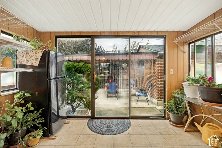 Sunroom featuring wood-look paneling, tiled flooring, and multiple windows