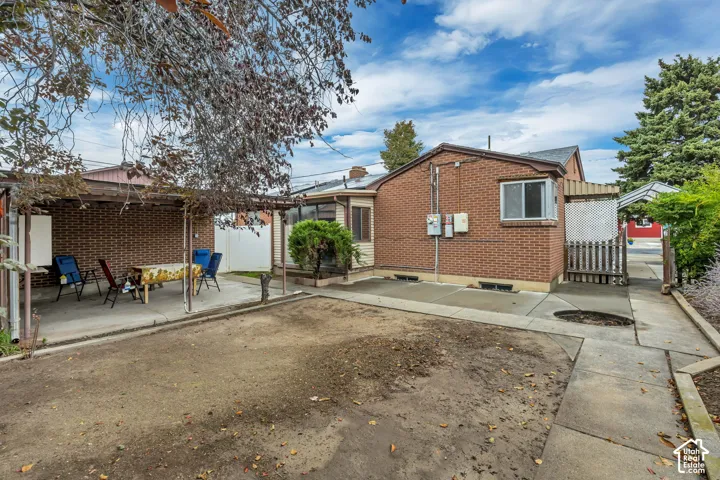 Brick exterior with a covered patio area, concrete pathways, and a detached structure