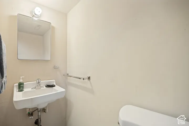 Wall-mounted porcelain sink with chrome faucet, complemented by a rectangular wall-mounted mirror