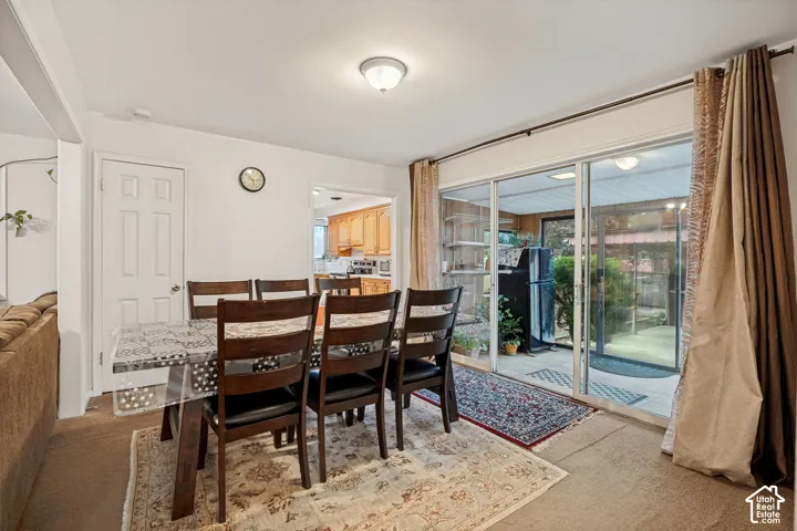 Sliding glass doors opening to an exterior patio area, ceiling-mounted light fixture, and a doorway opening to a kitchen area with wood-finish cabinetry