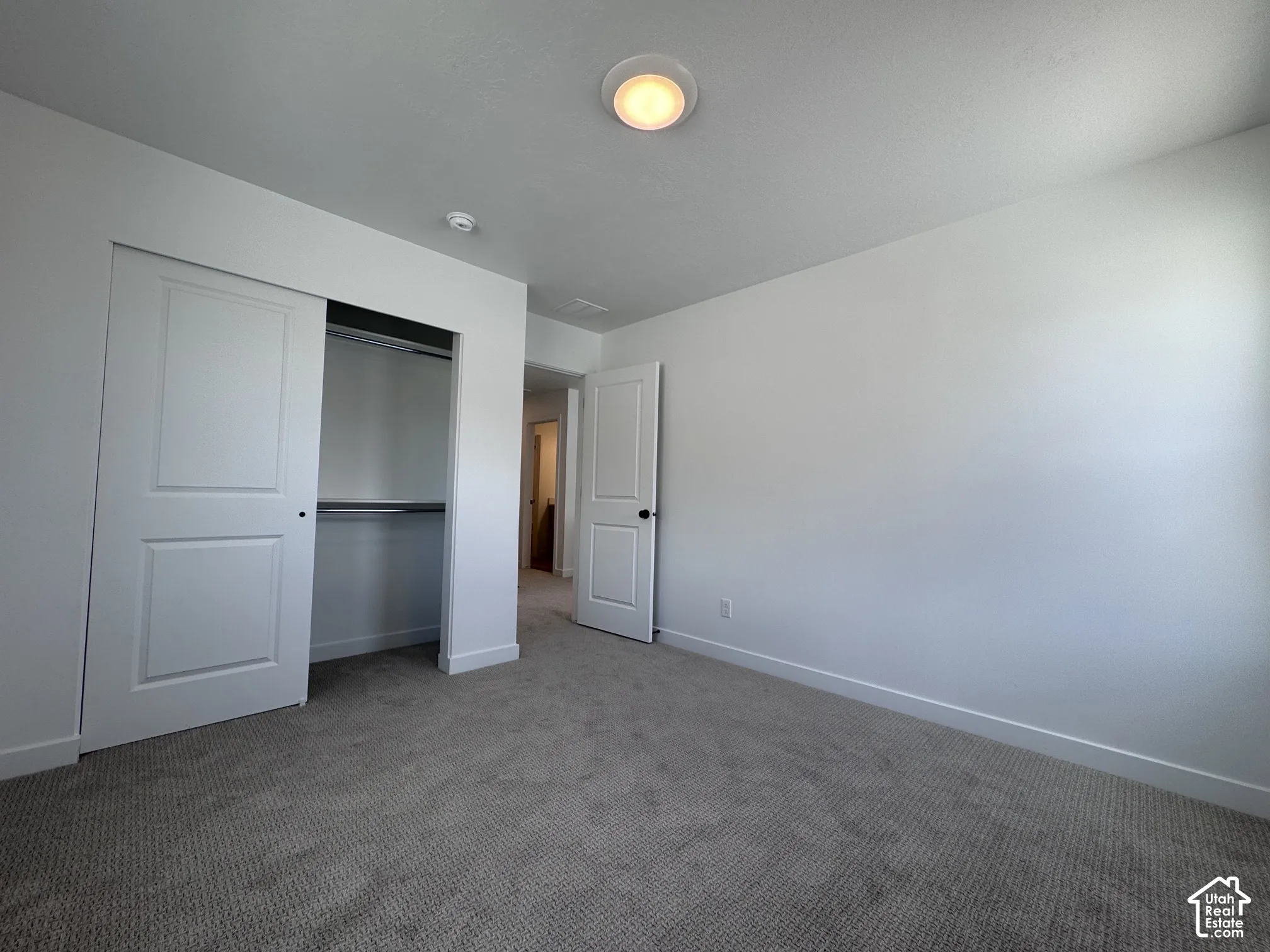 Neutral wall color, recessed ceiling light, paneled closet doors, built-in closet shelving, and gray carpet flooring