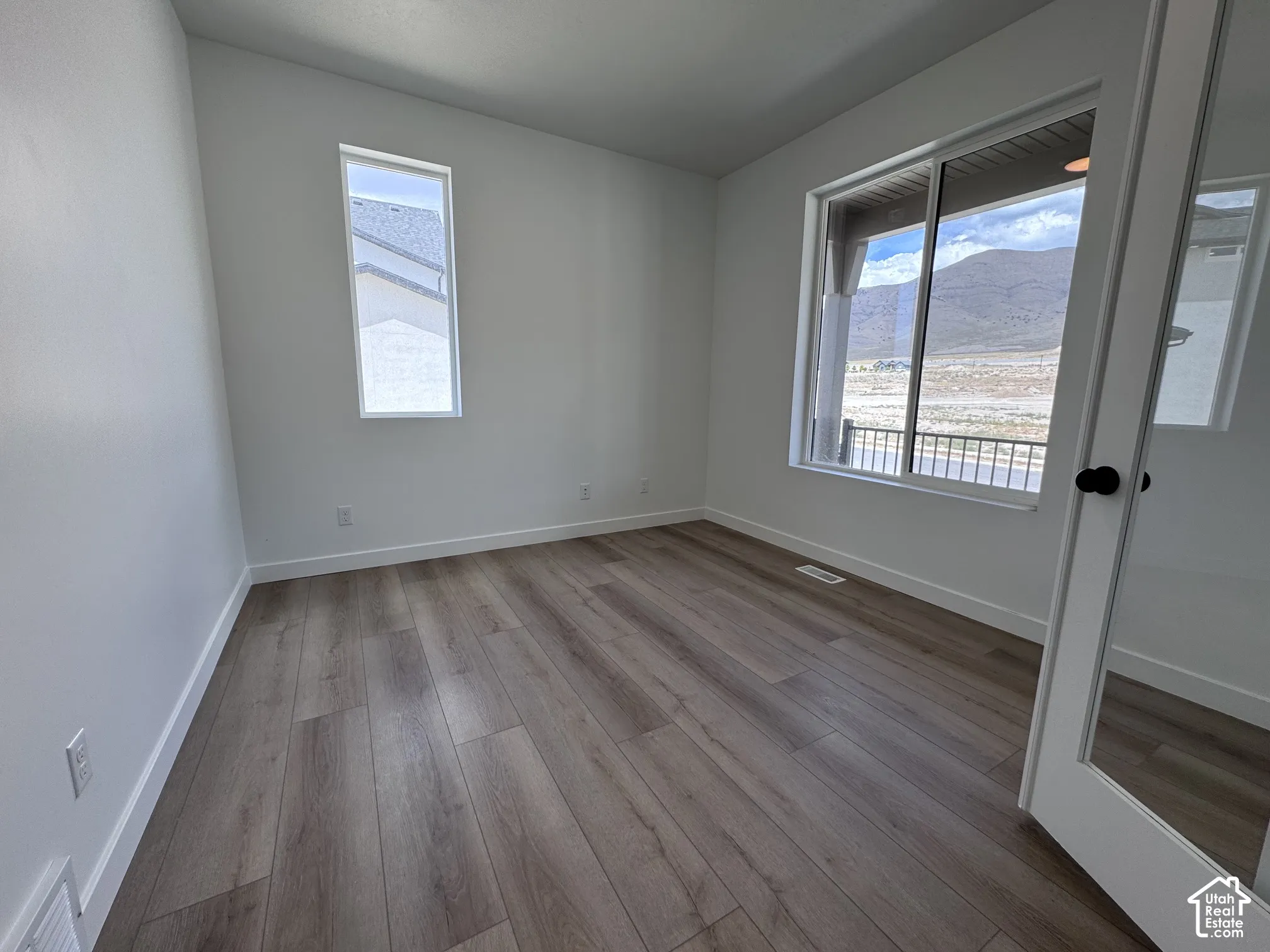 Wood-finish flooring, white walls, large window with outdoor scenery, and a vertical accent window