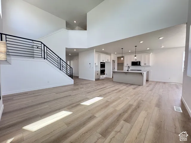 Vaulted ceilings with recessed lighting, wood-finish flooring, and a contemporary staircase with black metal railings
